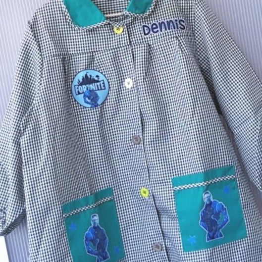 Bata escolar de cuadritos de color verde con botones con tus personajes favoritos